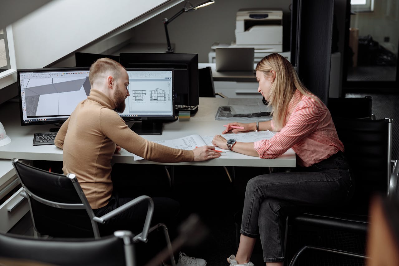 Two architects discuss plans in a contemporary office, focusing on project details.